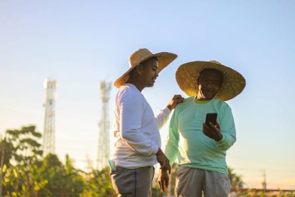 Farmers on the field with phone towers in the bg