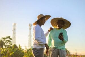 Farmers on the field with phone towers in the bg